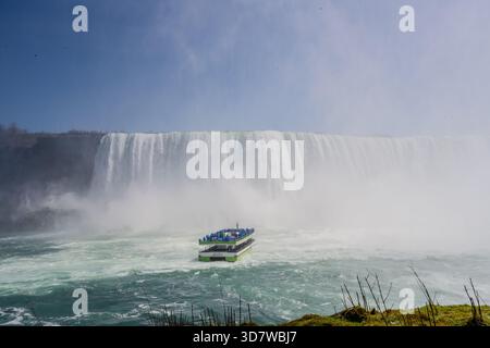 Un tour in barca trasporta i passeggeri in poncho antipioggia blu verso la base delle Horseshoe Falls alle Cascate del Niagara. La nebbia nasce dalla potente casca Foto Stock