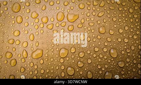 la ricca superficie metallica è punteggiata da numerose gocce d'acqua di varie dimensioni, creando una texture lussuosa e astratta. Sfondo ideale per il branding, Foto Stock