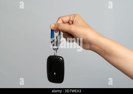 Mano che regge Un moderno telecomando per auto con design in fibra di carbonio Foto Stock