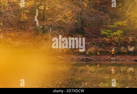 Donna che cammina nel paesaggio naturale con il lago autunnale Foto Stock