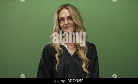 Donna sicura di sé con capelli biondi in uniforme da giudice su sfondo verde isolato. Foto Stock