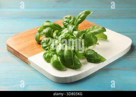 Foglie di basilico fresco su un tavolo di legno azzurro, primo piano Foto Stock