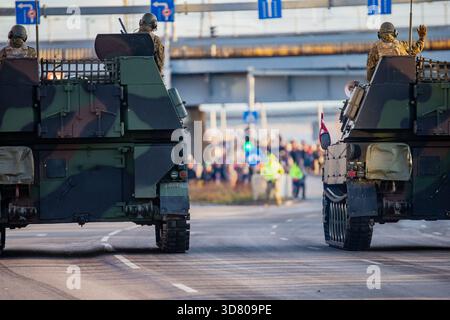 Convoglio militare NATO di portaerei corazzati che mostra soldati, superfici mimetiche e strutture posteriori rinforzate che avanzano attraverso un'area della città durante il def Foto Stock
