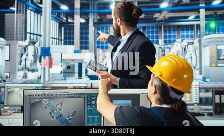 Il responsabile istruisce il dipendente dell'impianto di pannelli solari su come utilizzare il software CAD per ottimizzare i layout. Il supervisore della fabbrica fotovoltaica insegna ai lavoratori come predisporre la massima potenza, la telecamera A. Foto Stock