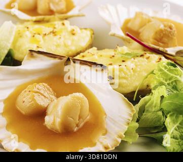 Cibo, capesante scottate con burro sul piatto Foto Stock