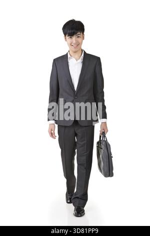 Un giovane uomo d'affari tiene in mano la valigetta e cammina, ritratto a figura intera isolato su sfondo bianco Foto Stock