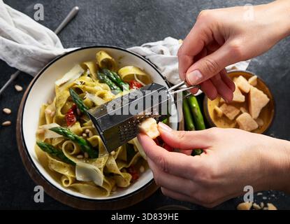 Fituccine con pesto di basilico e pinoli su un piatto bianco. Fituccine al pesto secondo una tradizionale ricetta italiana su un backgroun scuro Foto Stock