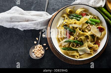 Fituccine con pesto di basilico e pinoli su un piatto bianco. Fituccine al pesto secondo una tradizionale ricetta italiana su un backgroun scuro Foto Stock