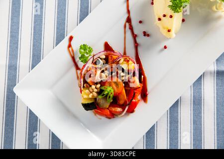 Ratatouille francese placcata gourmet con melanzane arrostite, peperoni e zucchine, guarnite con pinoli e riduzione balsamica. Foto Stock