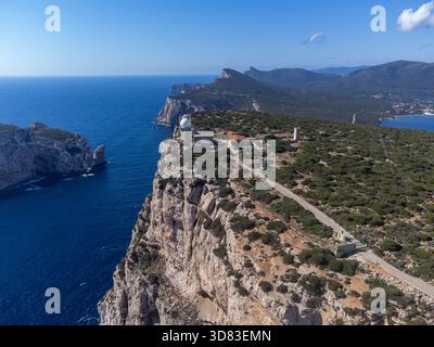 Splendida vista aerea del promontorio di Capo caccia in Sardegna, Italia. L'iconico faro bianco si trova in cima alla scogliera calcarea a strapiombo, dramatica Foto Stock
