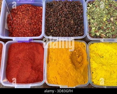 Spezie vivaci e frutta secca esposte in contenitori presso un mercato Foto Stock