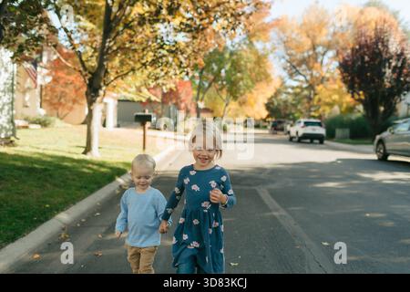 Fratelli che camminano mano nella mano sulla strada autunnale Foto Stock