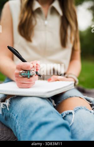 Primo piano di una donna che scrive su un notebook con anello turchese Foto Stock