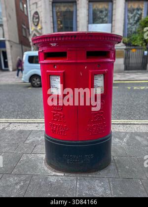 L'iconica scatola a colonna rossa brillante della Royal mail in una City Street nel Regno Unito Foto Stock