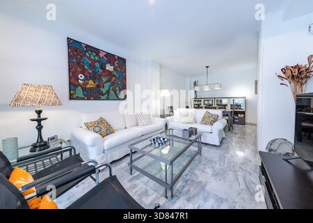 Spazioso soggiorno interno con divani bianchi e grande dipinto nella casa di vacanza Foto Stock