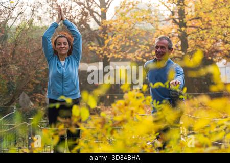 Coppie mature che praticano yoga stretching all'aperto nel parco autunnale Foto Stock