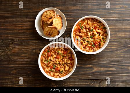 Gulasch americano, piatto con manzo macinato e maccheroni a gomito in salsa di pomodoro su fondo di legno. Vista dall'alto, disposizione piatta Foto Stock