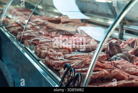 Una vivace esposizione di vari tagli di carne in una macelleria, che presenta una varietà di prodotti freschi sotto vetro. Foto Stock