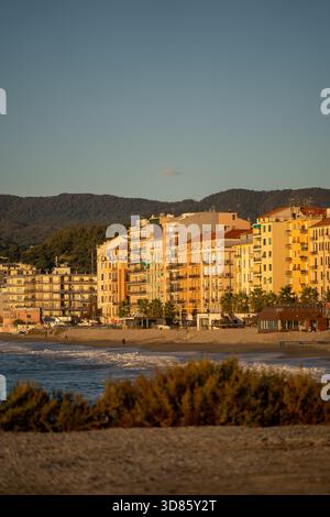 la costa illuminante dell'alba offre un'atmosfera tranquilla, onde dolci e facciate luminose all'alba sulla spiaggia Foto Stock
