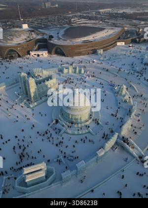 Vista aerea di un paesaggio innevato caratterizzato da sculture di ghiaccio e folle di persone vicino all'Harbin Ice and Snow World, che creano uno spettacolo invernale abbagliante Foto Stock
