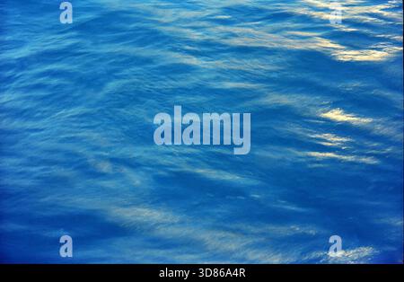 Primo piano astratto di acqua marina blu ondulata con riflessi della luce del sole sulla superficie Foto Stock