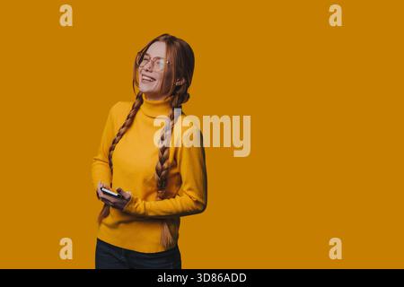 Donna rilassata che indossa un maglione giallo che interagisce con il suo telefono Foto Stock