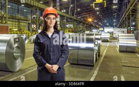 Giovane tecnico donna con casco e occhiali che lavora in un'acciaieria Foto Stock