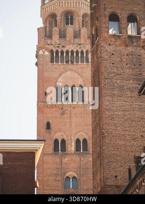 Cremona, Italia 3 ottobre 2025 Torrazzo Campanile a Cremona, Italia intricate murature medievali e archi gotici che si innalzano contro un cielo azzurro limpido, Foto Stock