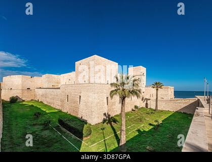 Vista panoramica del castello normanno di Trani in Puglia con fossato, torri e palme Foto Stock