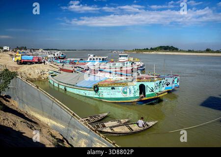 Le colorate barche fluviali attraccate lungo la trafficata costa con piccole barche e camion in legno Foto Stock