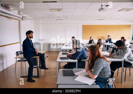 Professore di sesso maschile che insegna agli studenti delle scuole superiori in classe Foto Stock