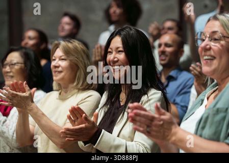 Donna matura sorridente che si esibisce in piedi ovando in teatro Foto Stock
