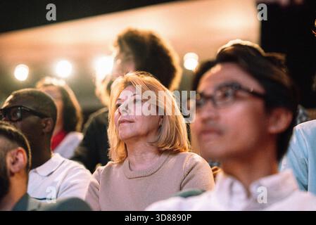 Vista ad angolo basso della donna anziana che guarda giocare mentre è seduta sul palco Foto Stock