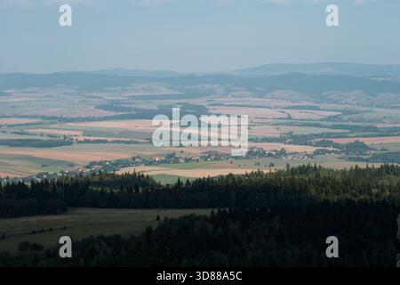 Ampio paesaggio di colline e vallate densamente boscose, con un piccolo borgo tradizionale visibile in lontananza Foto Stock