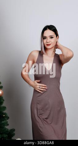Donna in abito marrone con albero di Natale sullo sfondo Foto Stock