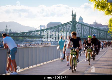 Persone che camminano e pedalano lungo il fiume in città Foto Stock