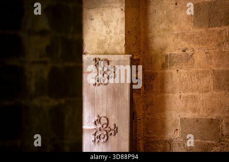 Antica porta in legno con ornati lavori in ferro all'interno di Mont Saint-Michel. Interni rustici medievali con cerniere decorative su una vecchia porta in legno. Foto Stock