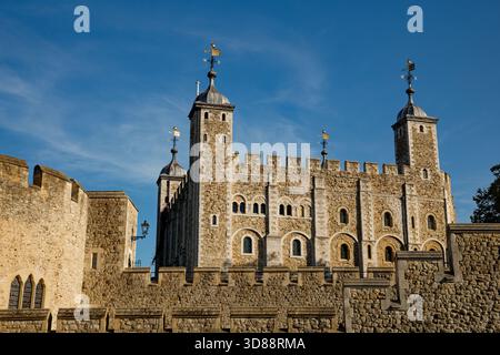 L'iconica Torre Bianca della Torre di Londra sorge sopra i battei della cortina muraria in un cielo blu, City of London, Inghilterra. Foto Stock