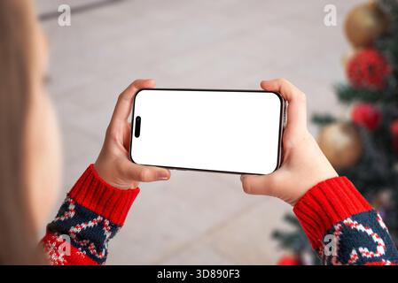 Modello telefonico orizzontale con maglione natalizio e decorazioni natalizie, perfetto per design natalizi, app invernali, interfacce di gioco e marke stagionali Foto Stock