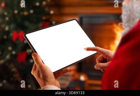 Tablet Babbo Natale con schermo vuoto in un accogliente interno natalizio, ideale per i mockup natalizi, il marketing invernale, le app per le feste e i desi digitali stagionali Foto Stock