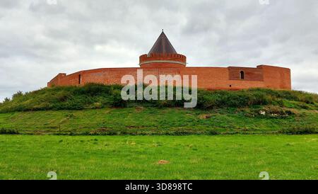 Castello fortezza in mattoni rossi Lindau con torre rotonda su una collina erbosa sotto il cielo grigio nuvoloso. Foto Stock