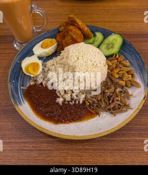 Piatto tradizionale malese di Nasi Lemak con riso, sambal, pollo fritto, acciughe secche e uovo salato Foto Stock