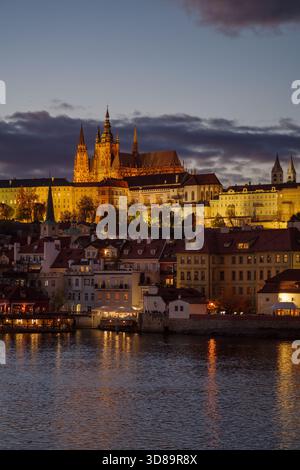 Vista notturna del Castello di Praga e della città minore con il fiume Moldava in primo piano Foto Stock