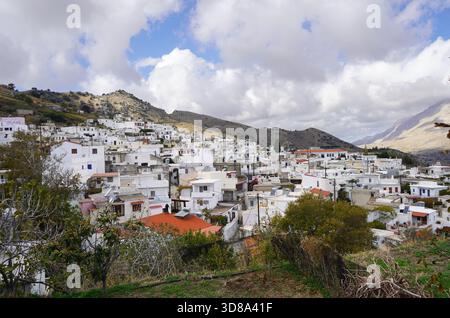 Ampia vista sul villaggio di Melampes, incastonato tra le montagne di Rethymno, Creta. Le case bianche si estendono lungo il pendio della montagna sotto un cielo spettacolare Foto Stock