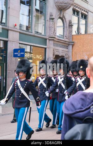 I soldati danesi in alti caschi in pelle d'orso sfilano per le strade di Copenaghen, Danimarca, le loro espressioni focalizzate sono chiaramente visibili Foto Stock