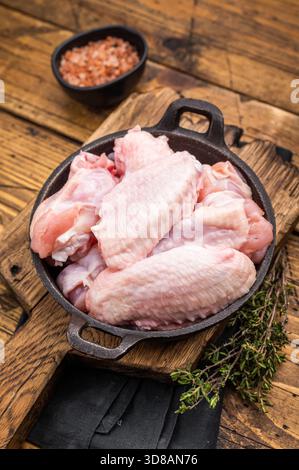 Succose ali ali di pollo crude, un ingrediente versatile perfetto per friggere, cuocere o grigliare alla perfezione. sfondo in legno. vista dall'alto. Foto Stock