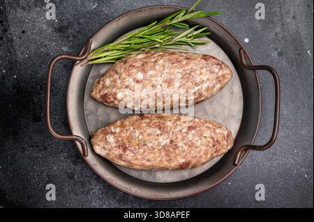 Kebab Kofta crudo appena preparato, marinato con spezie, pronto per la cottura alla griglia e pieno di sapore. sfondo nero. vista dall'alto. Foto Stock