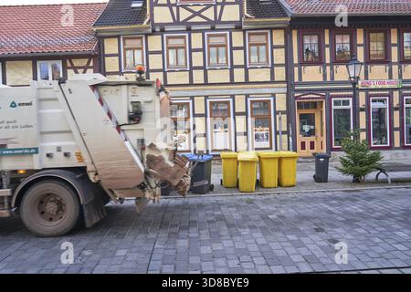 I contenitori per la raccolta dei rifiuti sono pronti per la raccolta pubblica dei rifiuti al mattino presto sulla Breite Strasse Wernigerode, nell'edificio protetto dal patrimonio culturale di Brei Foto Stock