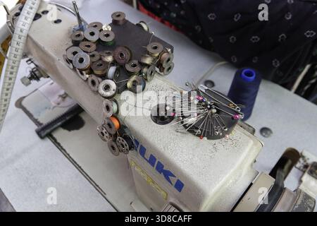 Little India, Singapore, 9 settembre 2025 Thimbles of thread e biglie varie attendono il loro artigiano sopra una macchina da cucire in un repa di abbigliamento Foto Stock
