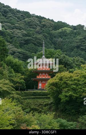 Una vista su una pagoda rossa a tre piani annidata nel profondo della lussureggiante foresta a livelli del complesso del tempio Kiyomizu-dera a Kyoto, in Giappone Foto Stock